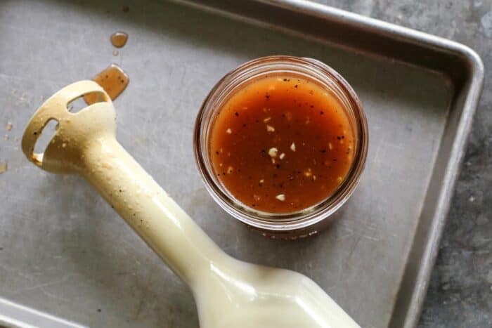 jar of salad dressing and an immersion blender on a pan