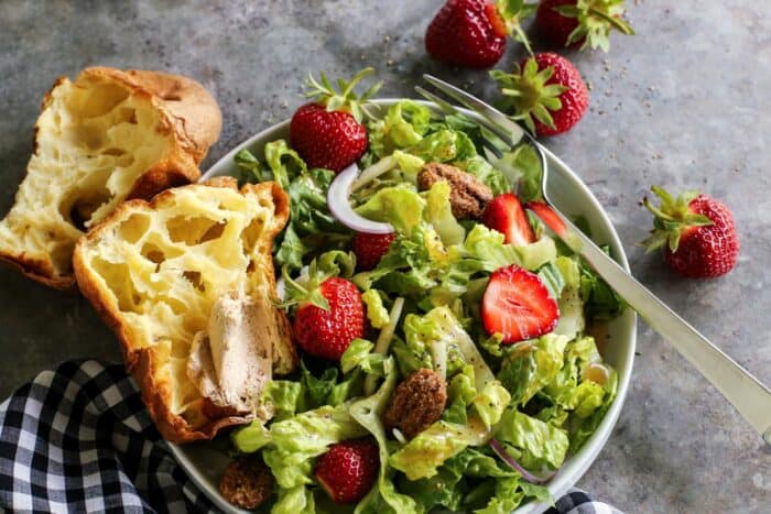 fresh salad of lettuce and strawberries on a white plate, with a popover