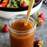red wine vinaigrette dressing in a jar, with a salad in the background