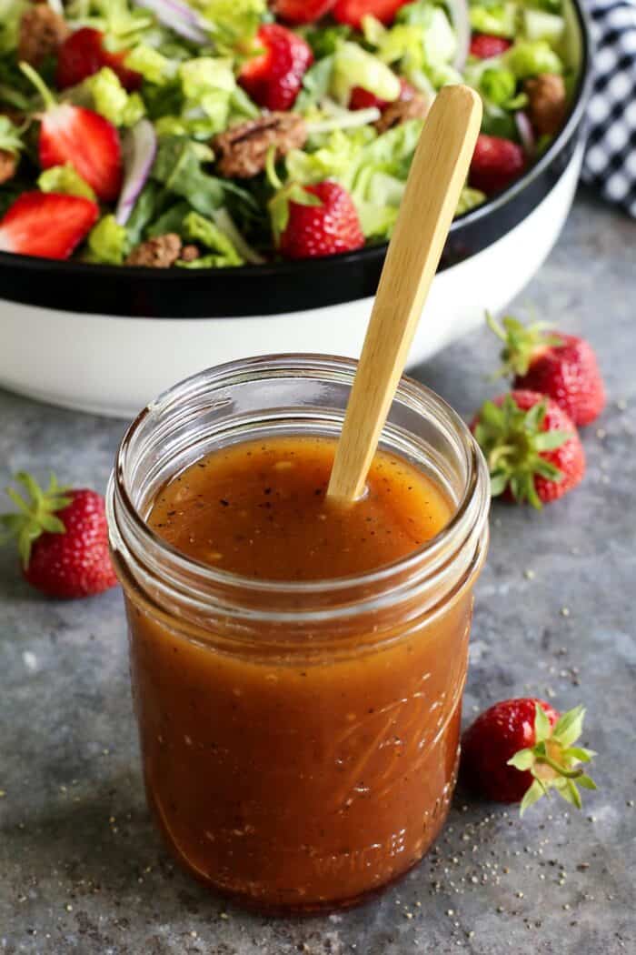 red wine vinegar dressing in a jar, with a salad in the background