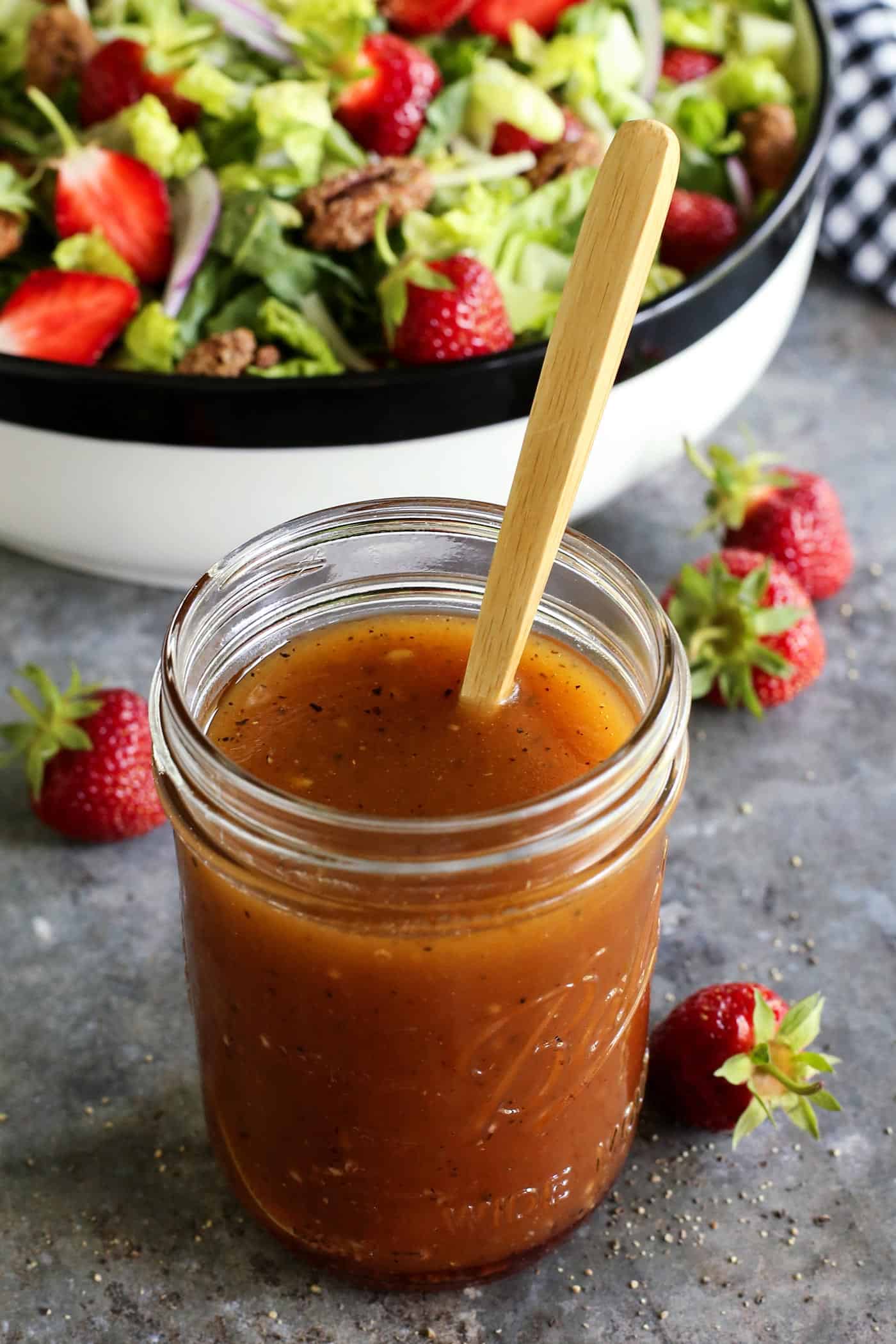 red wine vinaigrette dressing in a jar, with a salad in the background