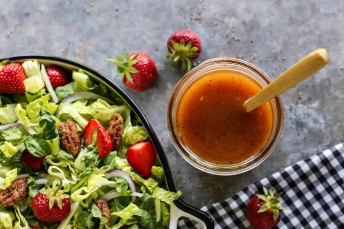 vinaigrette in a jar, by a lettuce and strawberry salad