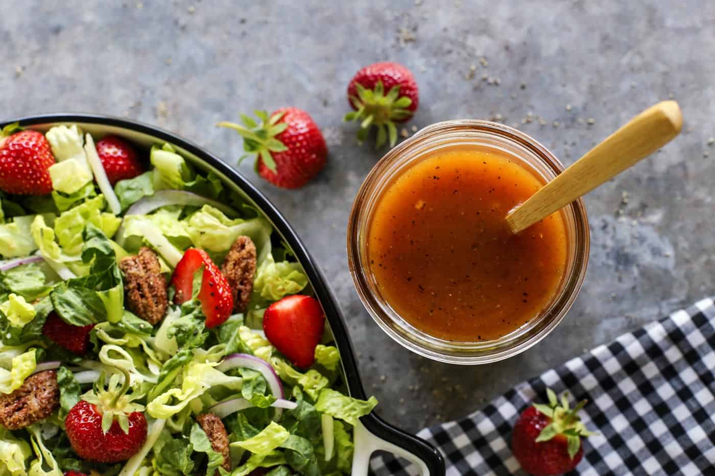 Red wine vinaigrette in a jar, by a lettuce and strawberry salad