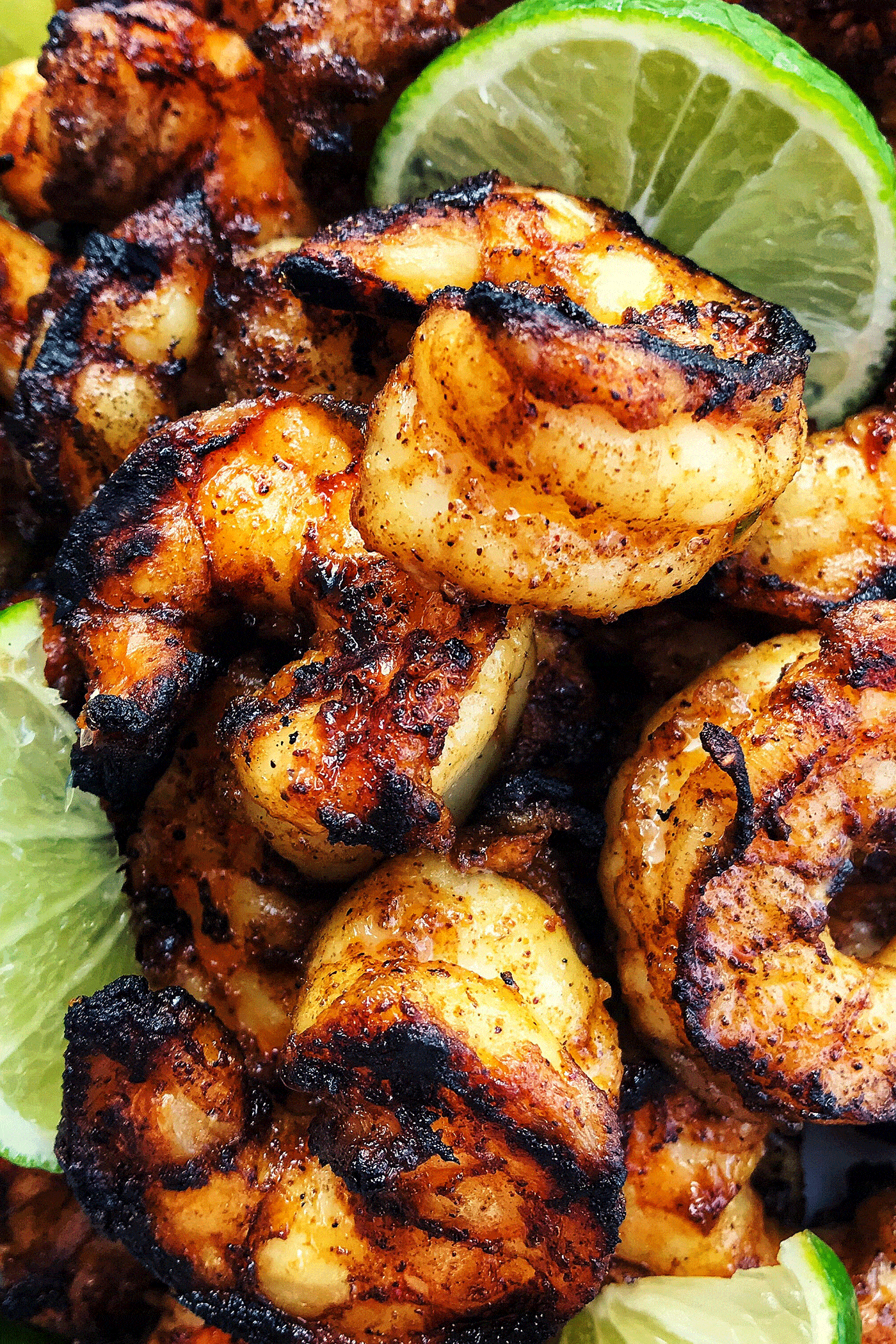 Jumbo shrimp that is charred from grill, with fresh lime wedges.