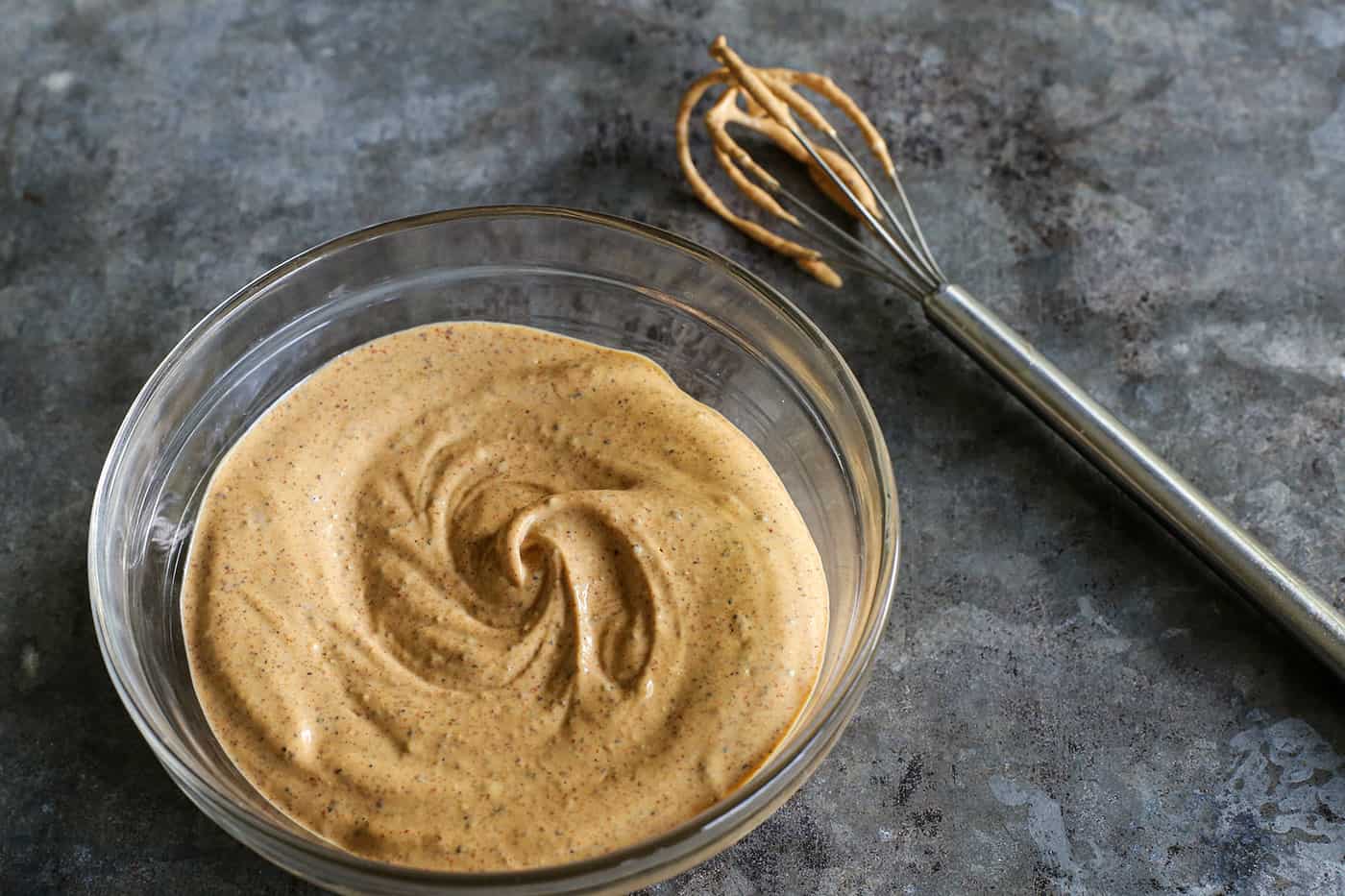 creamy dressing in a small clear bowl, plus a small whisk