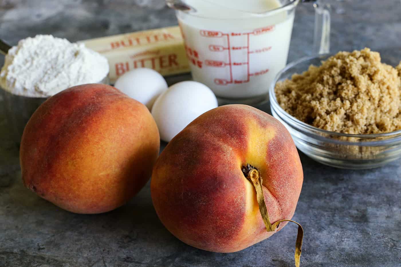 Le gâteau aux pêches tendre et parfumé est rempli de fruits de saison, incroyablement moelleux et recouvert de sucre à la cannelle. Pêches fraîches, farine, œufs, beurre, babeurre et cassonade