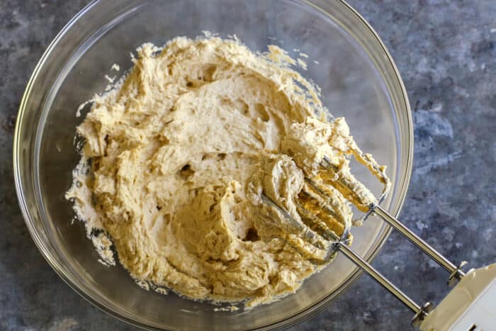 cake batter mixed in a clear bowl with an electric mixer