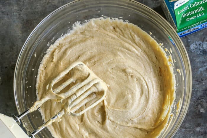 mixing cake batter in a clear bowl with an electric mixer, plus a box of buttermilk