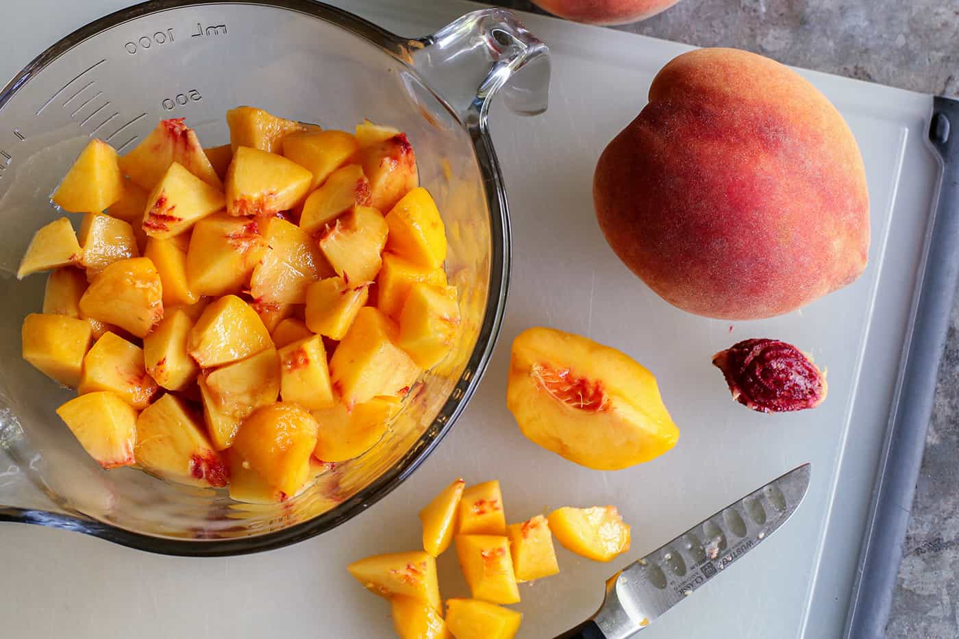 fresh whole peaches, plus a bowl of peeled, sliced peaches