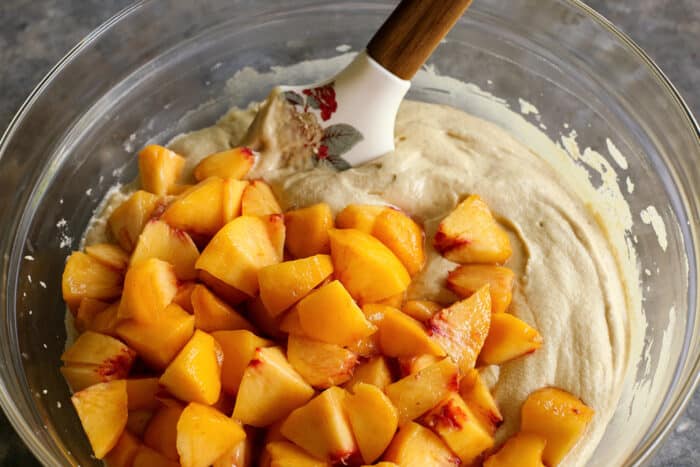 fresh sliced peaches on top of cake batter in a clear bowl