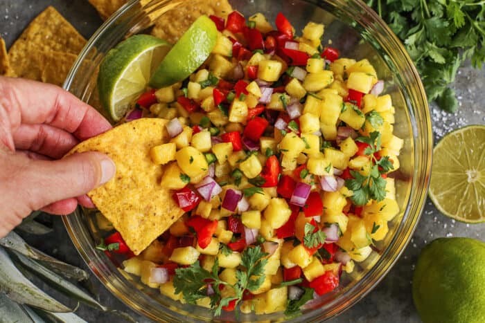 hand dipping a tortilla chip into fresh salsa