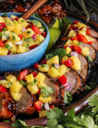 slices of pork tenderloin with pineapple salsa over the top and in a bowl