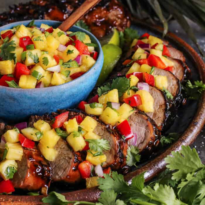 slices of pork tenderloin with pineapple salsa over the top and in a bowl