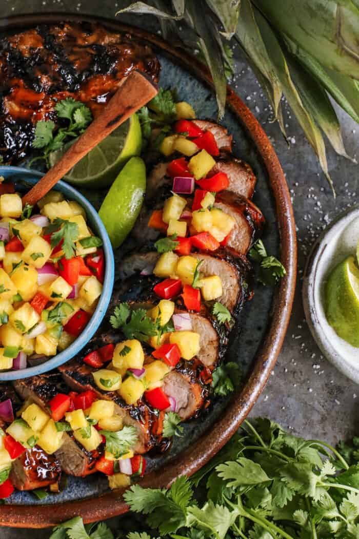 large pottery platter of sliced pork tenderloin with pineapple salsa