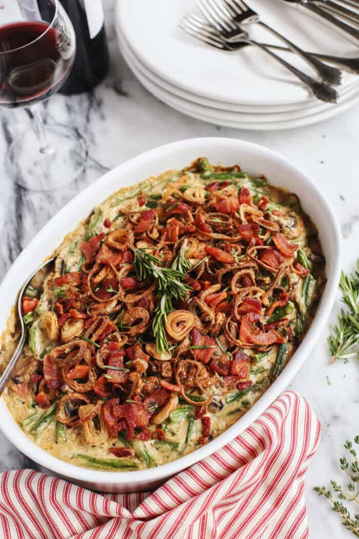 green bean casserole with bacon and crispy fried shallots in a white serving dish