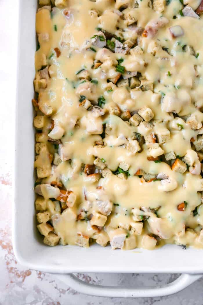 creamy sauce poured over turkey and stuffing mixture in large white serving dish