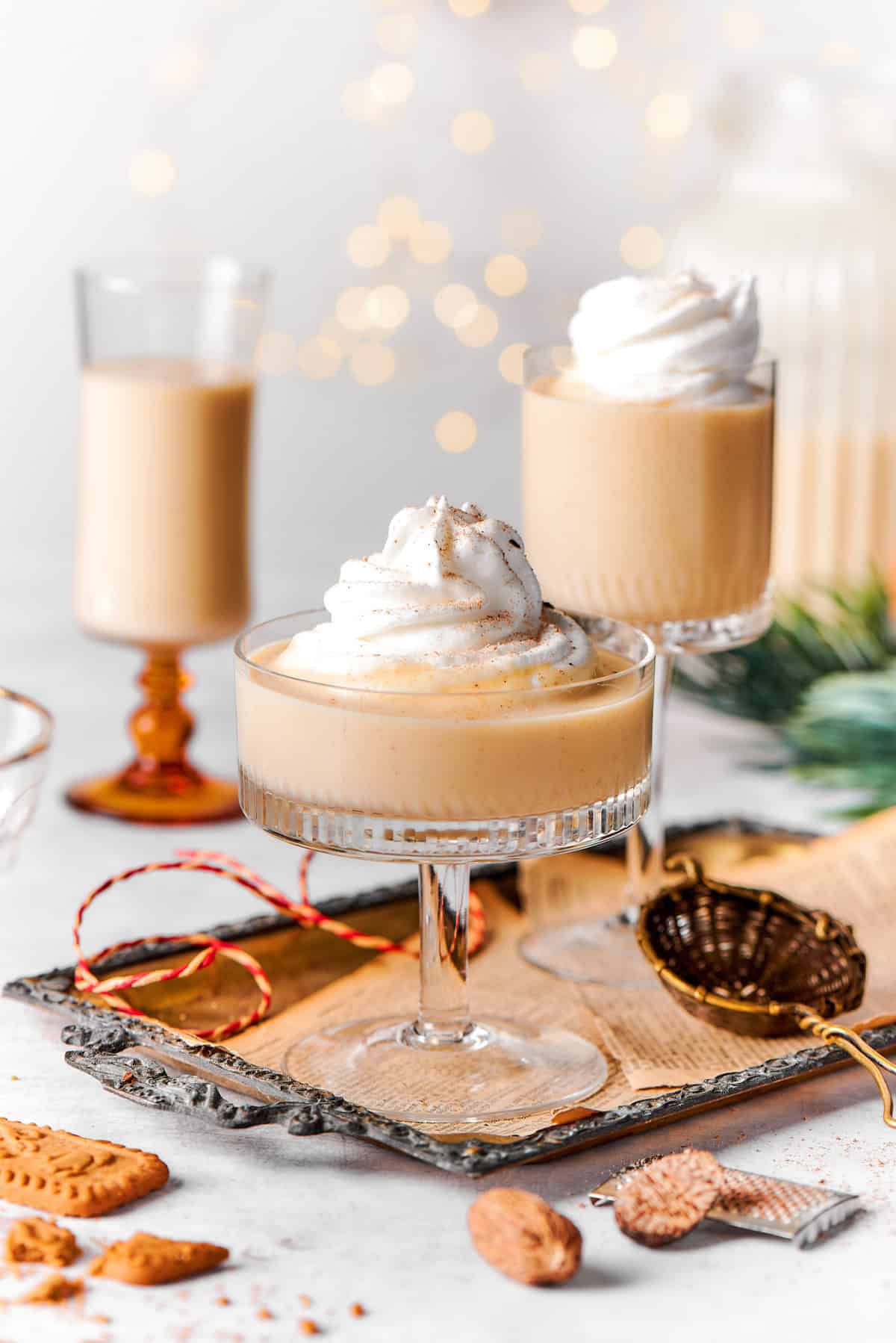 This spiced homemade eggnog recipe with brandy, smokey rum, and fluffy whipped cream is the perfect cocktail for holiday gatherings. Three glasses of creamy Christmas eggnog with whipped cream.