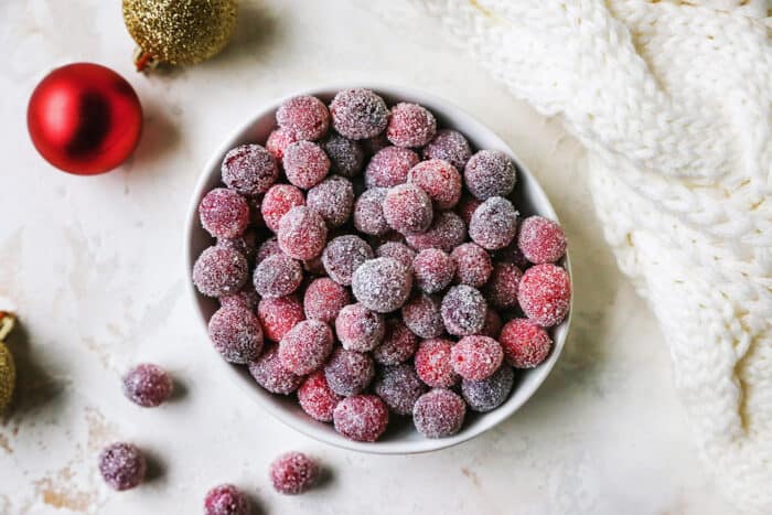 sugared cranberries, Christmas ornaments, and a comfy cream blanket