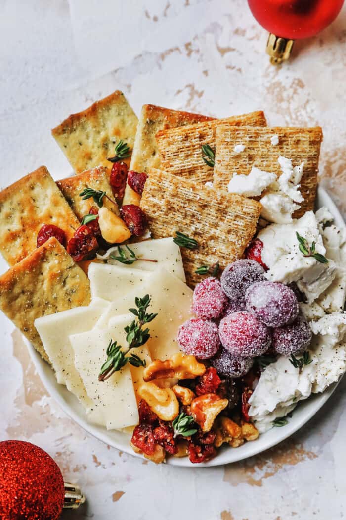 a plate of cheese, crackers, and nuts, plus candied cranberries