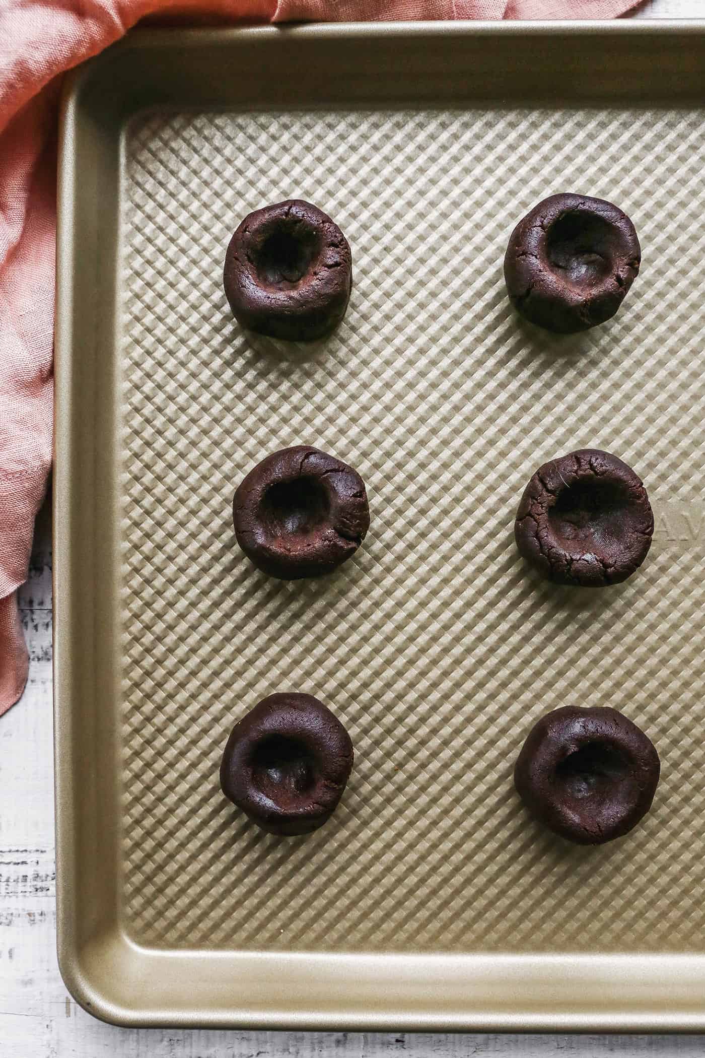 balls of chocolate cookie dough with a thumbprint in each one