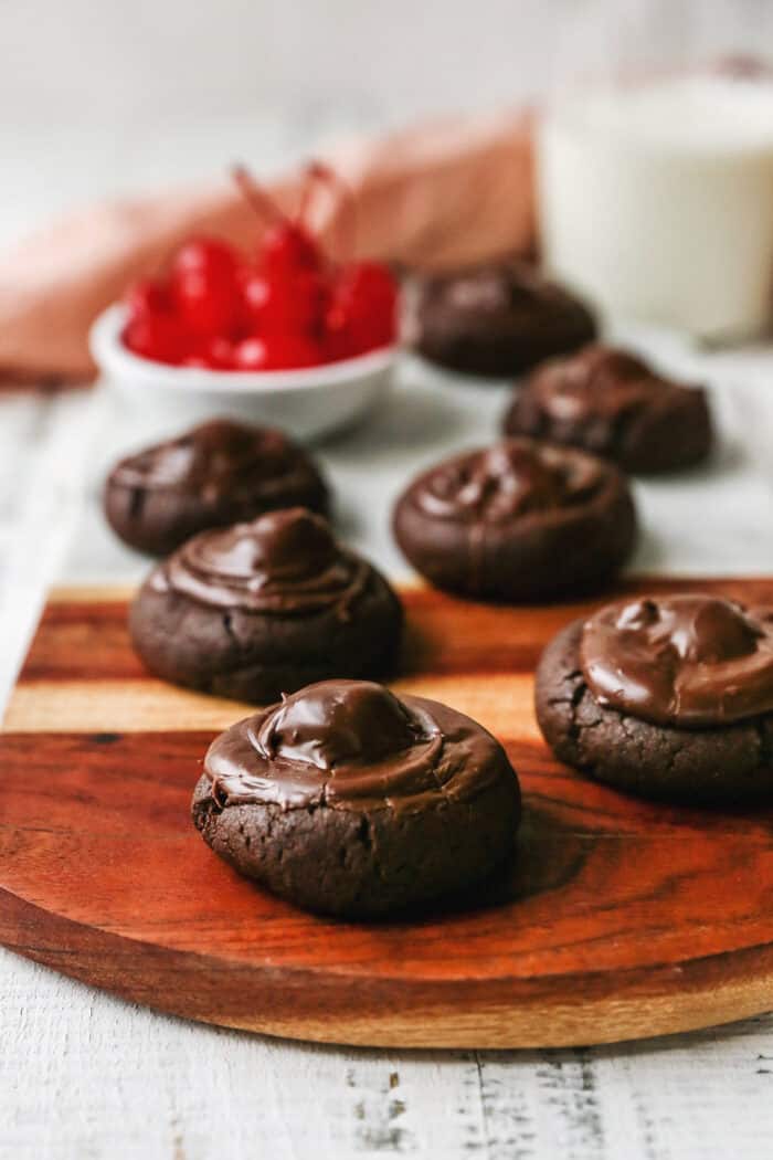 baked chocolate covered cherry cookies on a wood and marble board