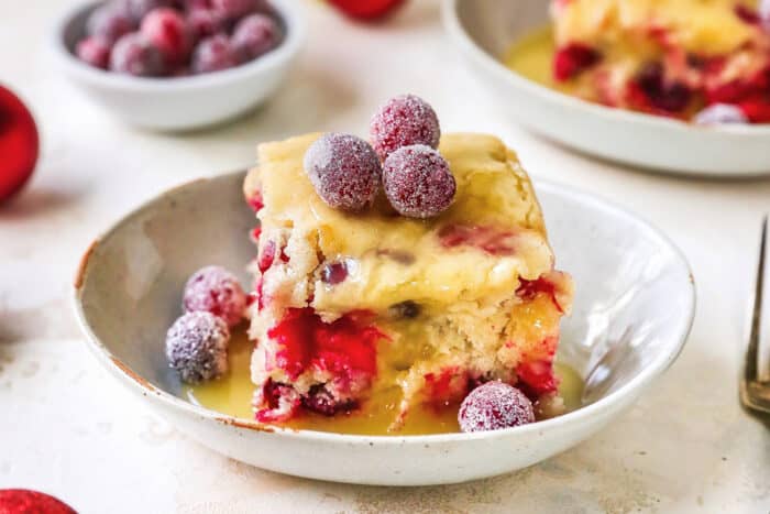 piece of cake with cranberries and butter cream sauce in a shallow dish