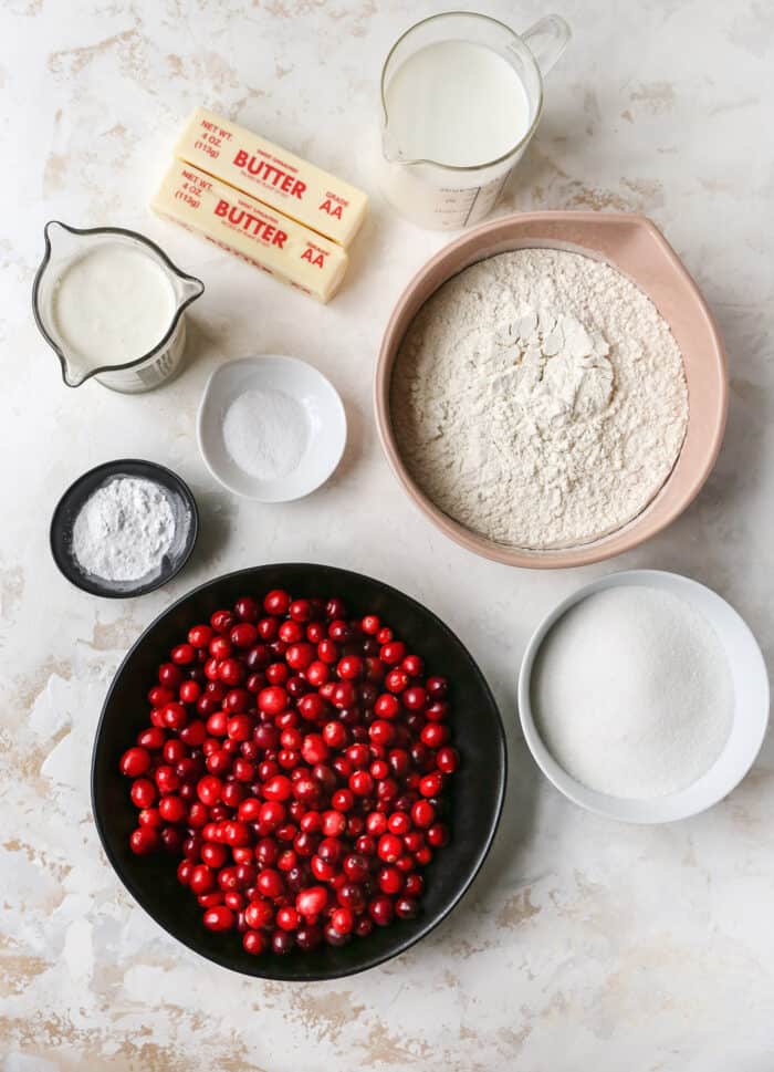 bowls of fresh cranberries, flour, sugar, baking powder, and salt, plus butter, milk, and heavy cream