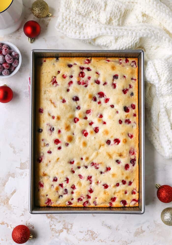 cranberry Christmas cake baked in a metal pan, with Christmas ornaments on the side