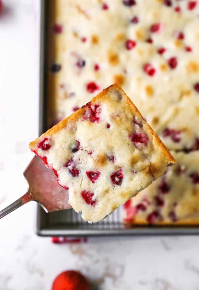 a spatula lifting a piece of Christmas cranberry cake out of the pan