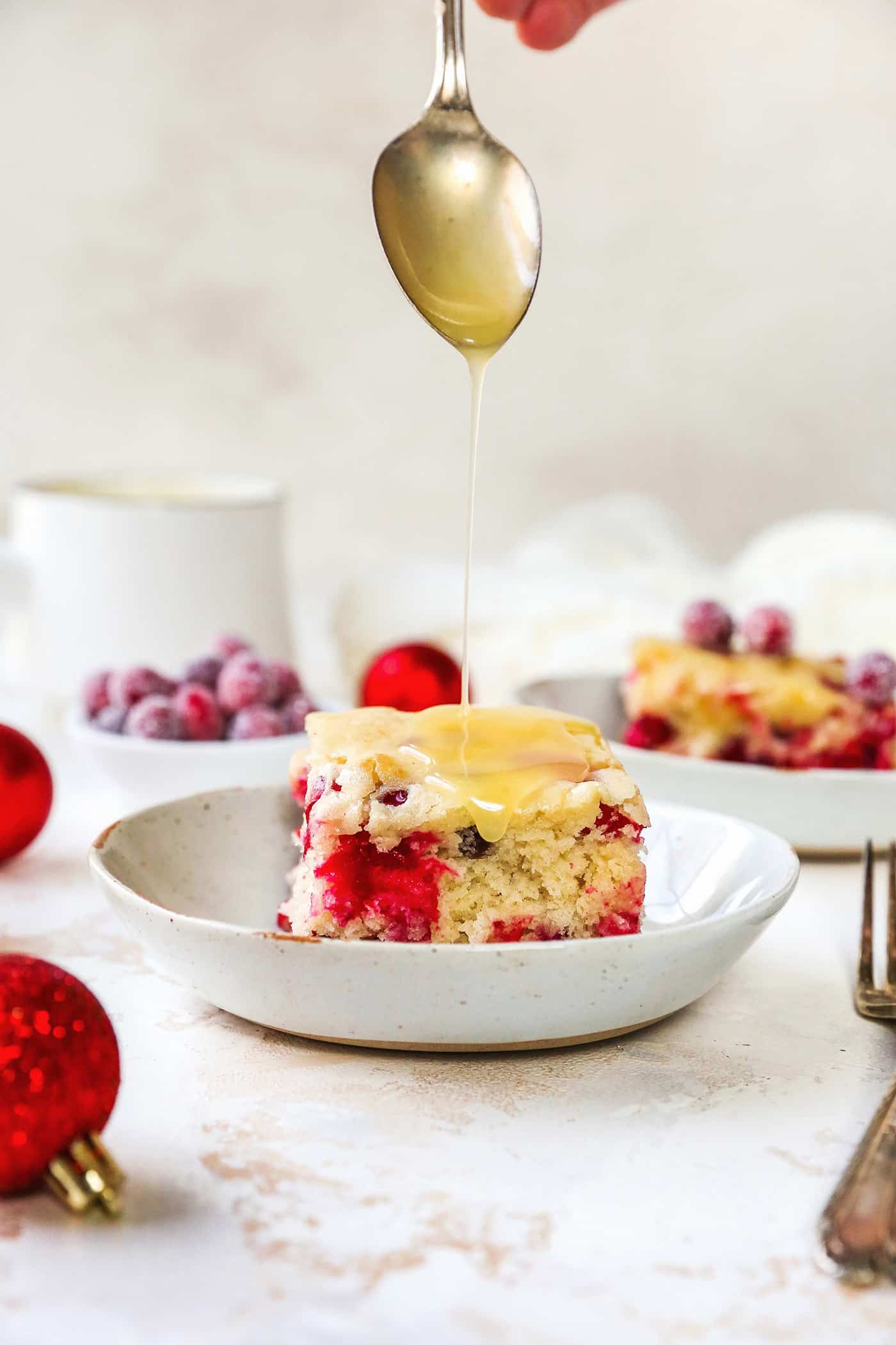 butter cream sauce being spooned over a piece of cranberry cake