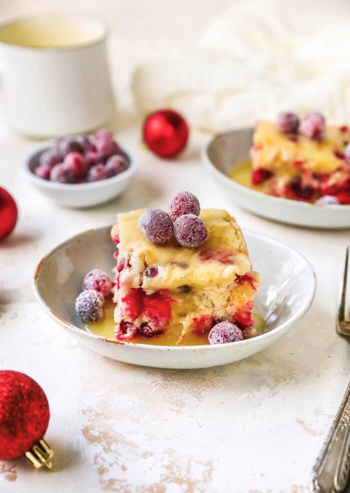 sugared cranberries on top of pieces of cranberry cake with butter cream sauce