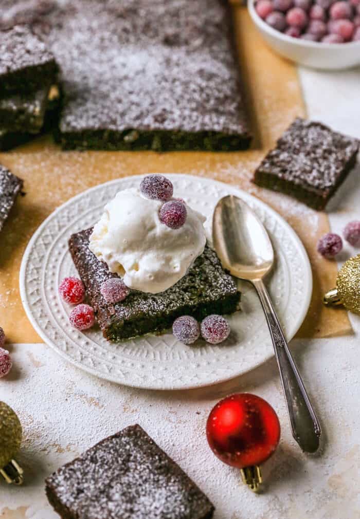a gingerbread brownie on a plate, plus Christmas ornaments and sugared cranberries