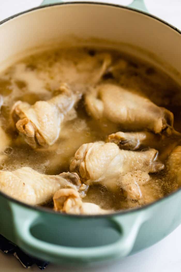 a large pot of water with chicken wings parboiling in it