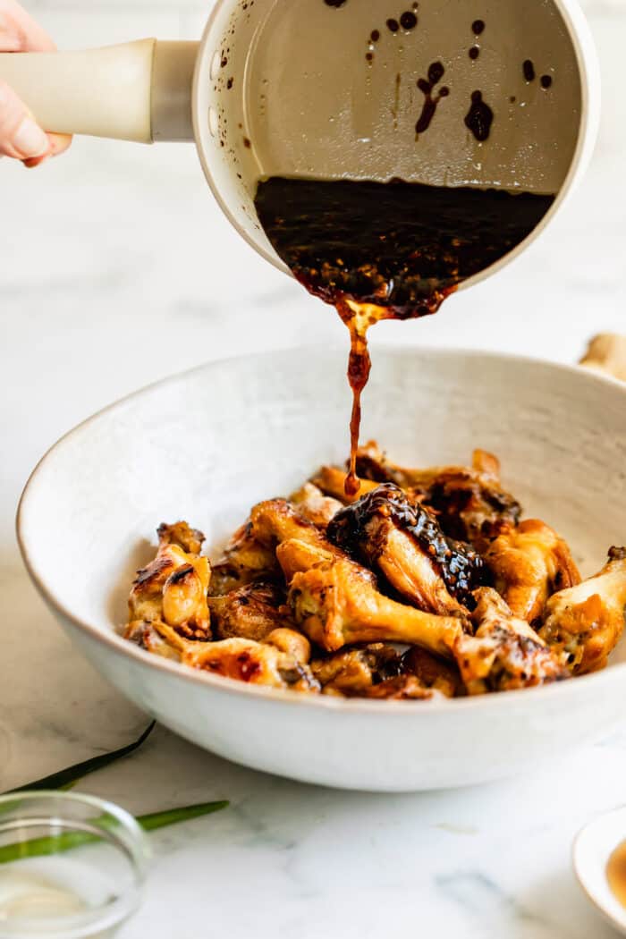 pouring oyster sauce over baked chicken wings