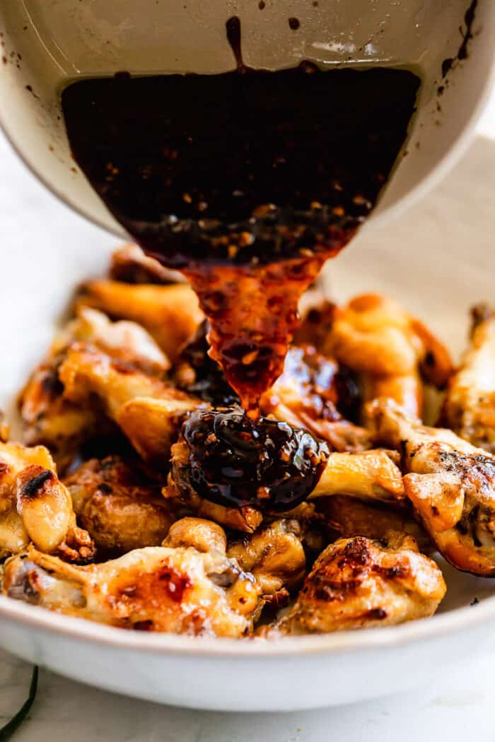 pouring oyster sauce over crispy oven wings