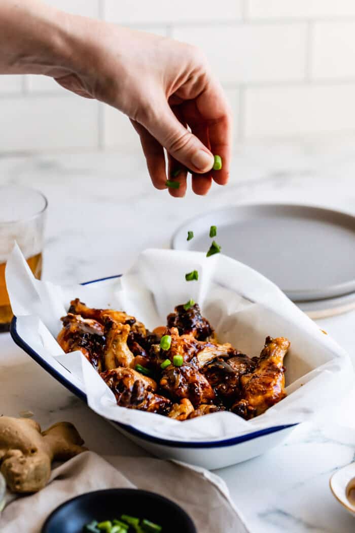 sprinkling chopped green onion over crispy oven baked chicken wings