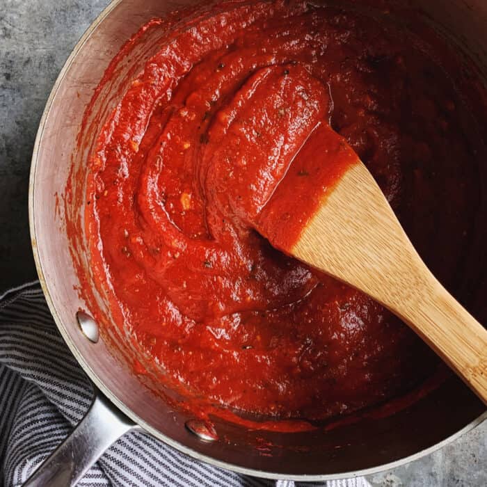 pizza sauce in a pan with a wooden spoon
