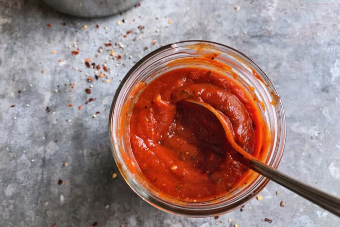 red sauce for pizza, in a jar with a spoon