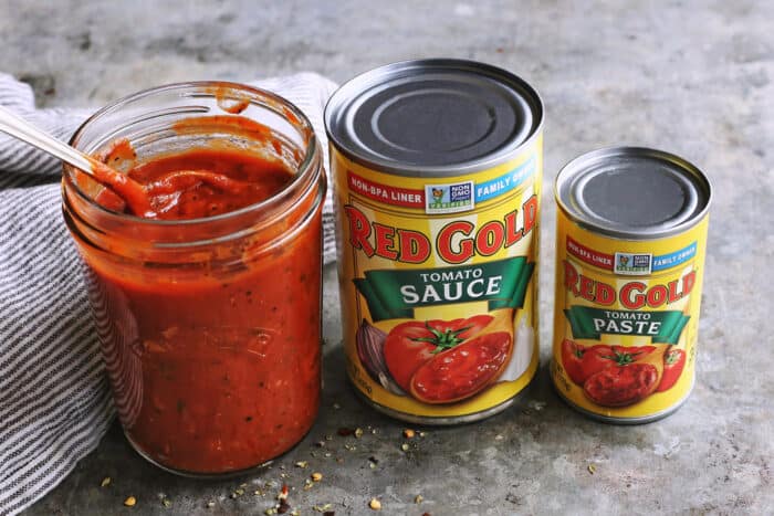 jar of homemade pizza sauce and a can of tomato sauce and tomato paste