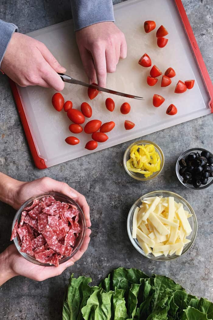 two people's hands, prepping a fresh Italian chopped salad