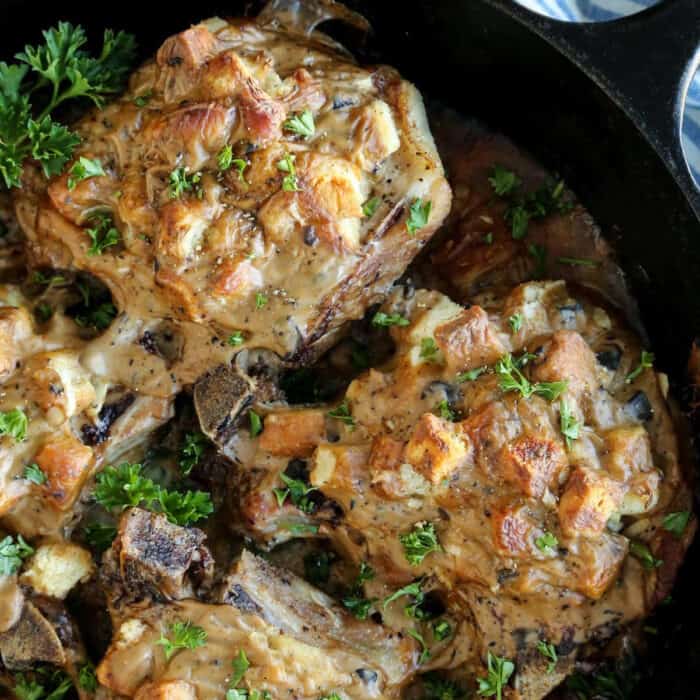 baked pork chops covered in stuffing, in a cast iron skillet