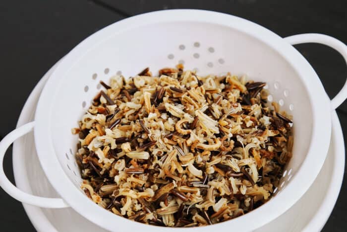 a white colander with cooked wild rice