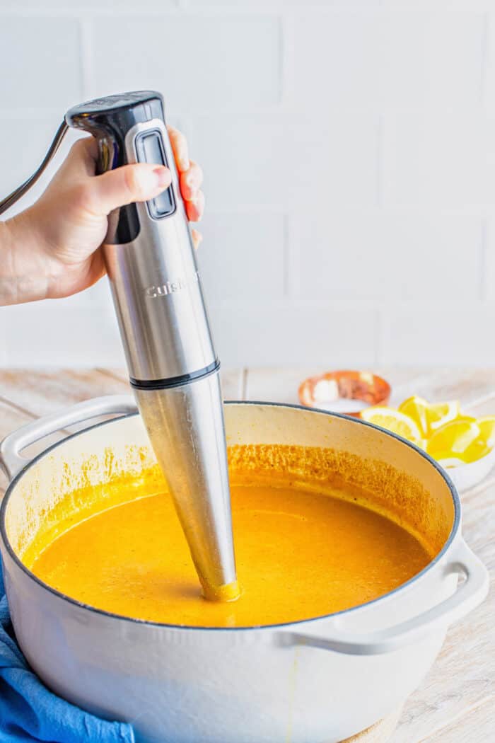 blending soup in a white pot with an immersion blender