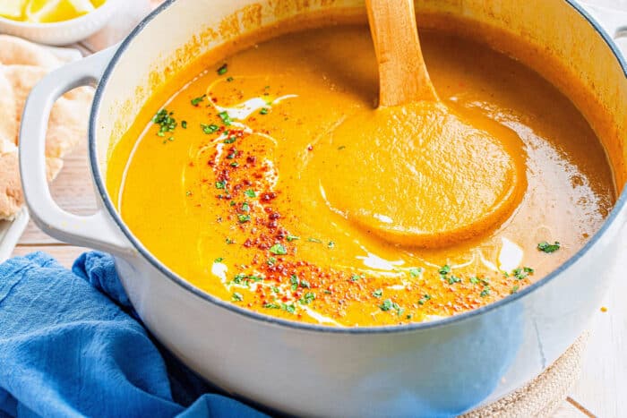 a white pot of lentil soup with a wooden ladle