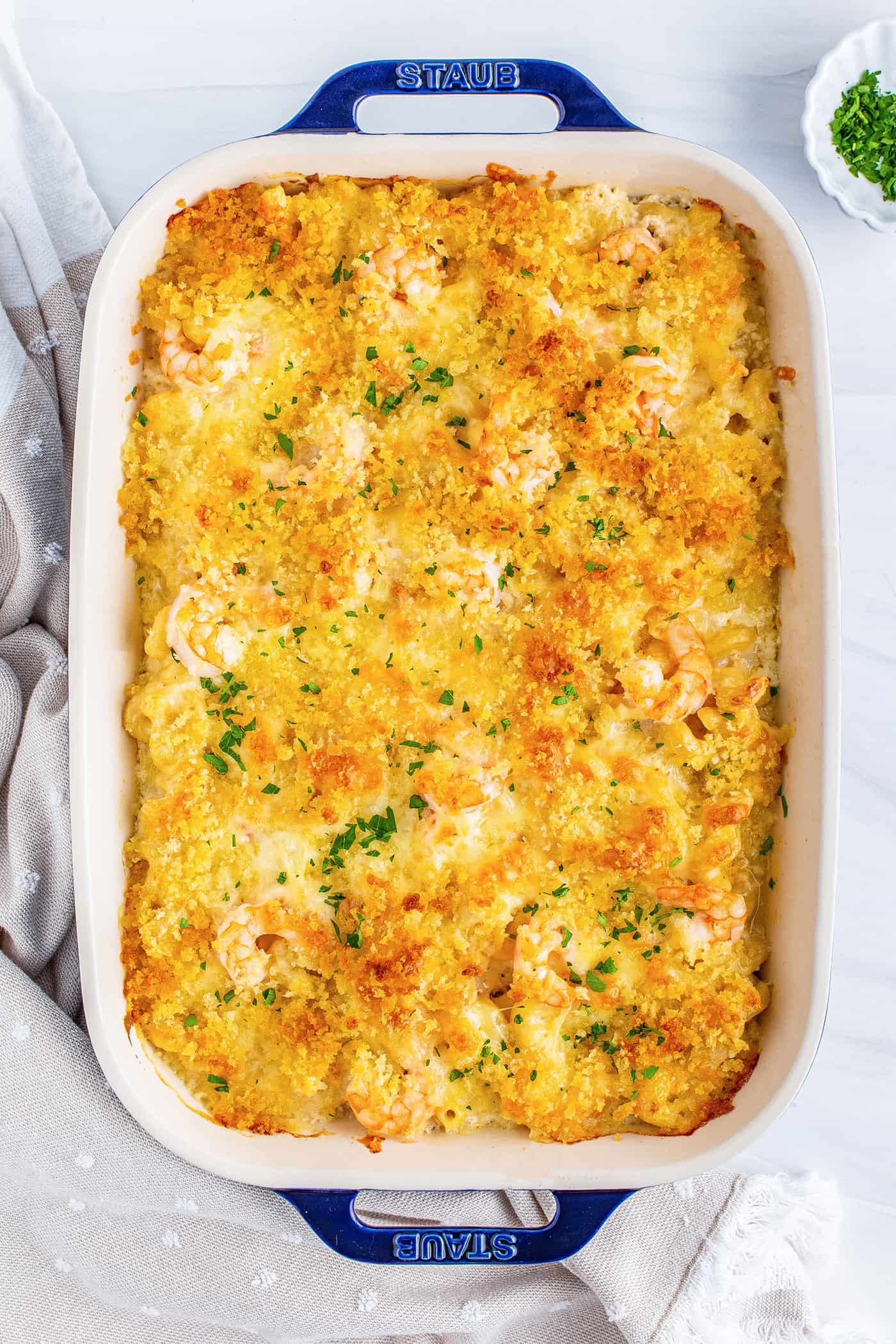 baked macaroni and cheese with shrimp and breadcrumb topping, in a blue 9" x 13" baking dish