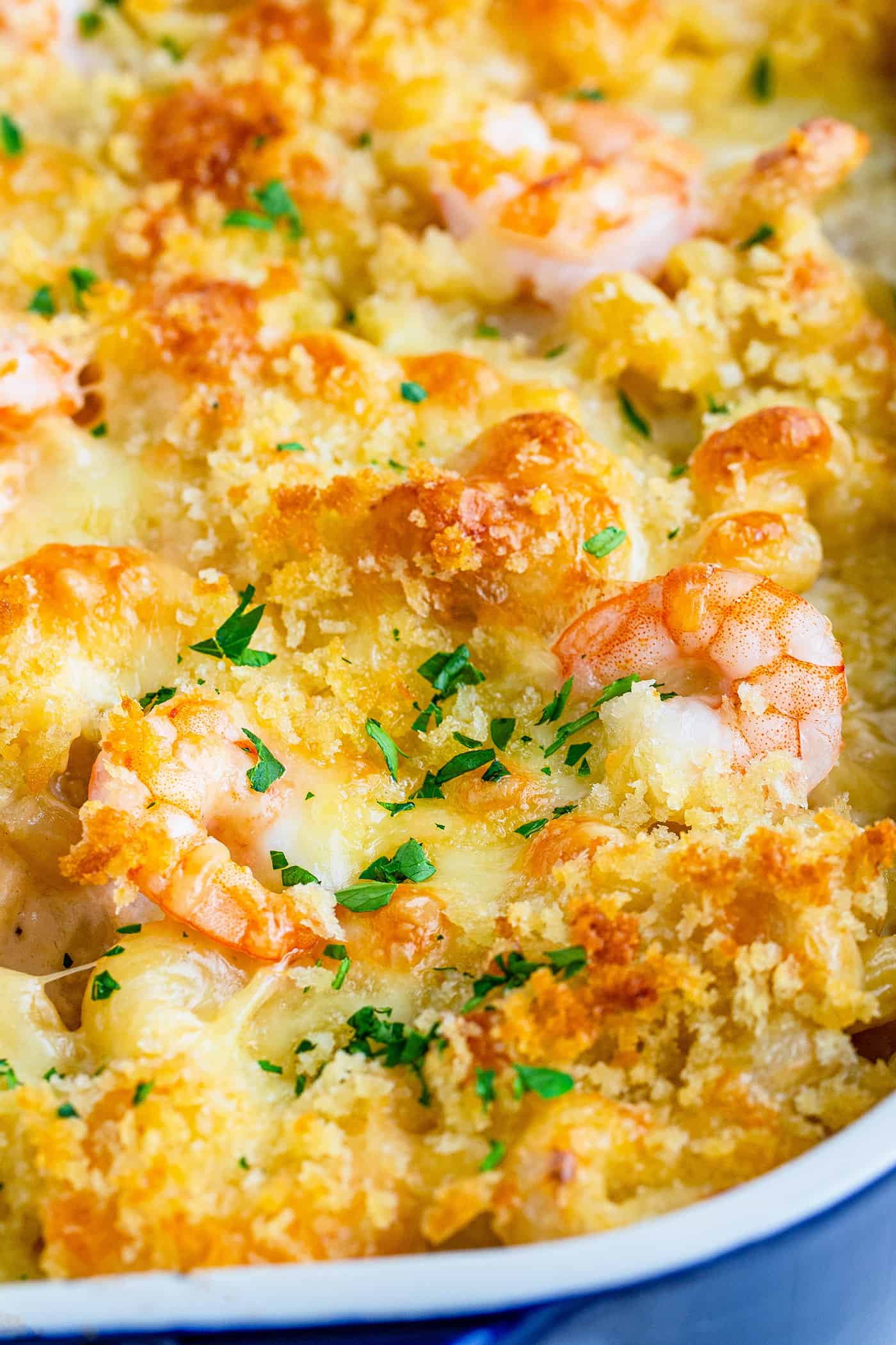 close-up of baked shrimp macaroni and cheese in a blue baking dish