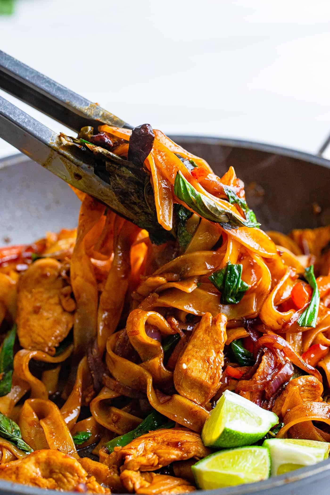 tongs lifting Thai noodles out of pan