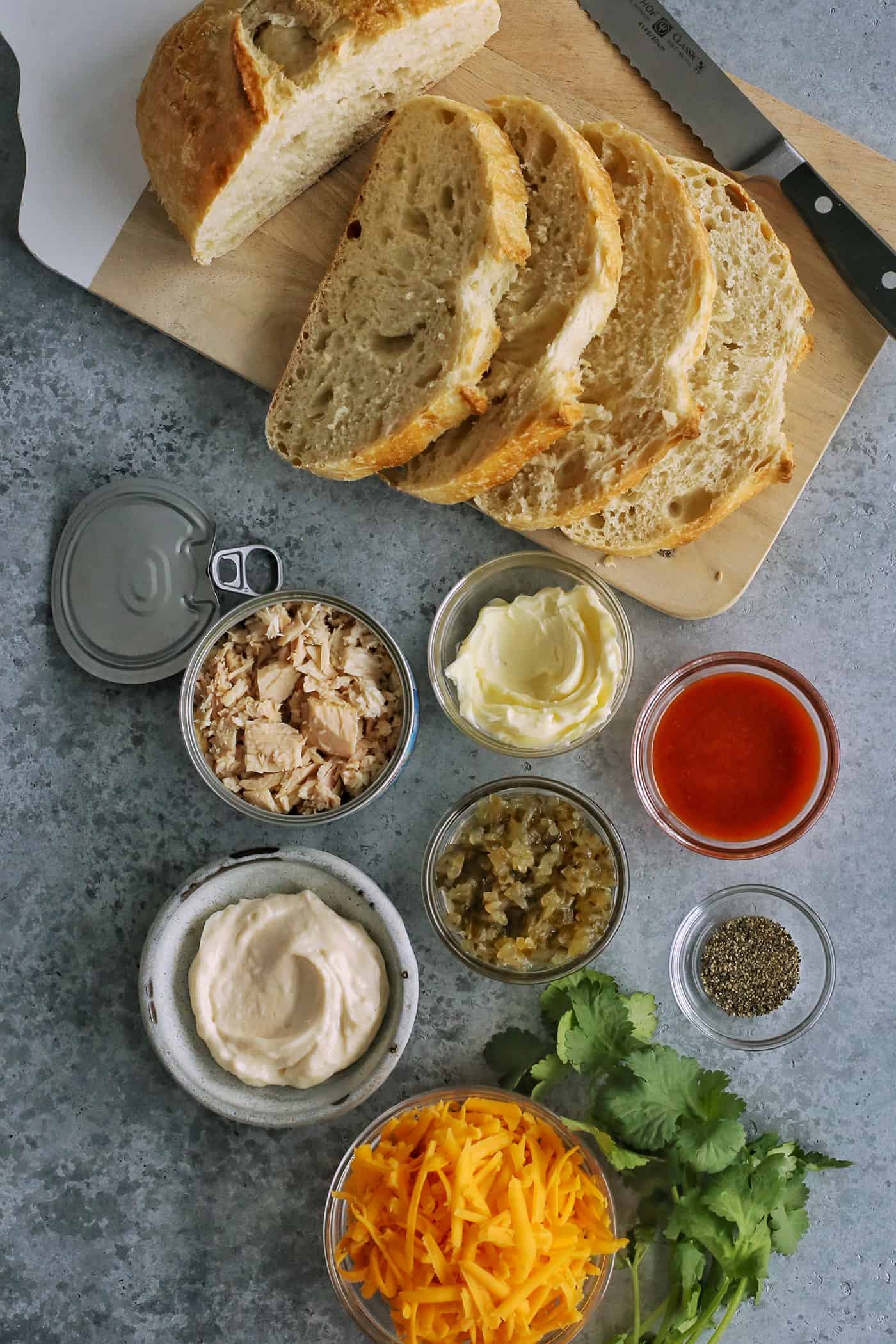 ingredients for a tuna melt - tuna, bread, butter, mayo, pickle relish, cheese, sriracha, cilantro, black pepper