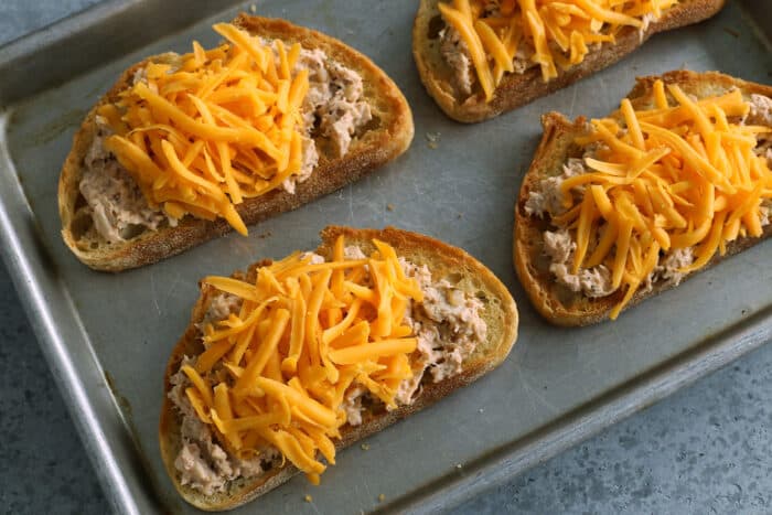 This spicy tuna melt recipe is a quick, easy hot sandwich with tuna, melty cheese, and spicy sriracha made warm and toasty in the oven! toasted bread topped with tuna salad and shredded cheddar