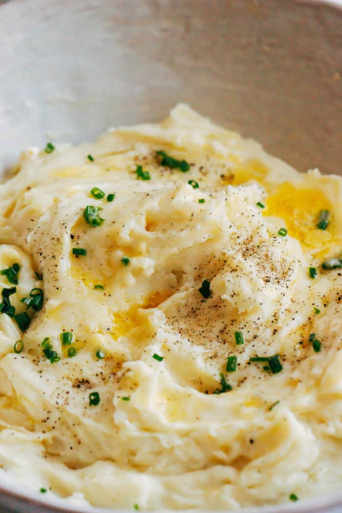 close-up photo of creamy mashed potatoes with melted butter and chives